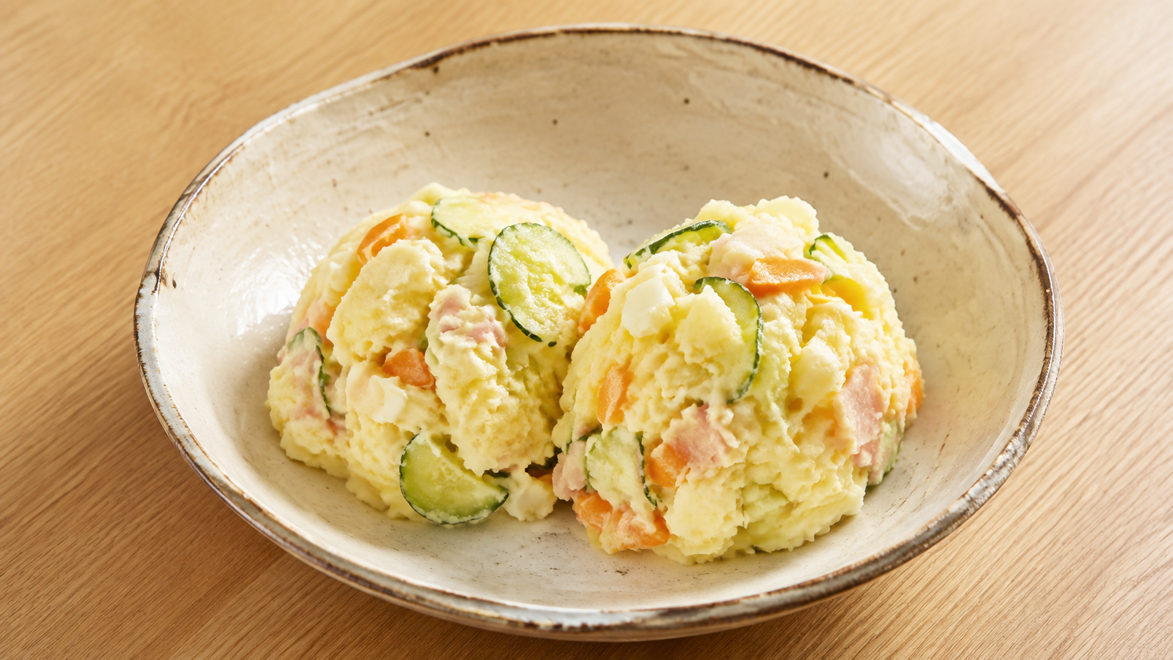 素朴な陶器にきゅうりやにんじん入りのポテトサラダを盛ったAI生成イメージ
